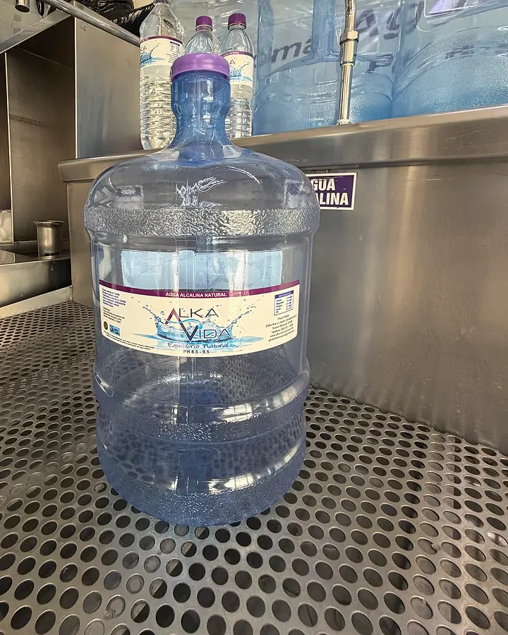 Garrafón de 11 litros con etiqueta de agua alcalina natural en el mostrador de la planta